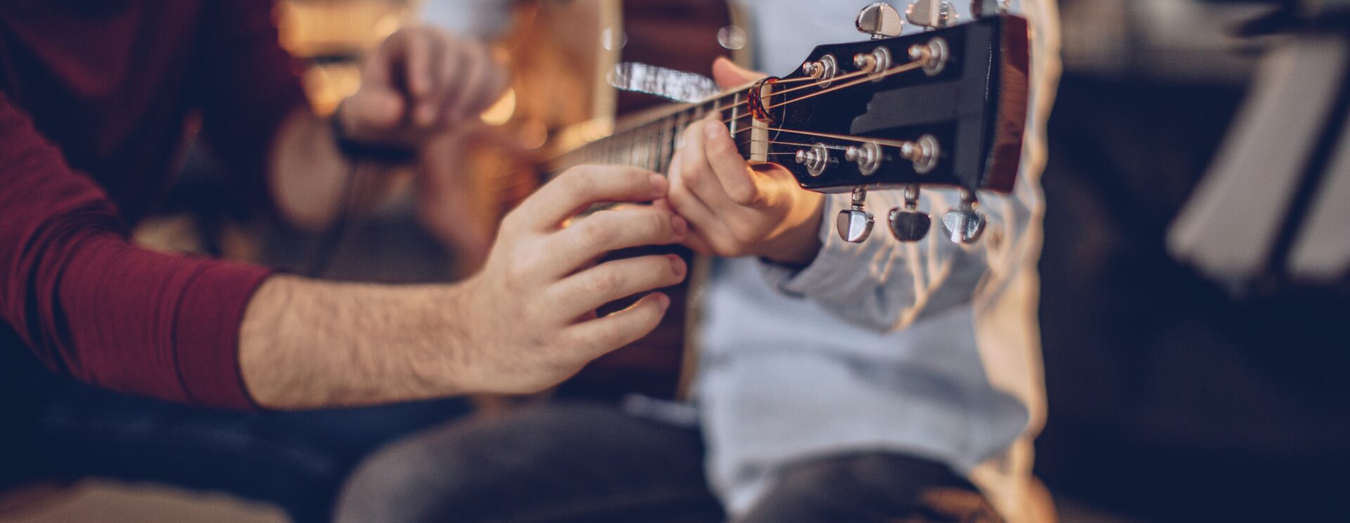 Enfant jouant de la guitare, accompagné, aidé d'un adulte